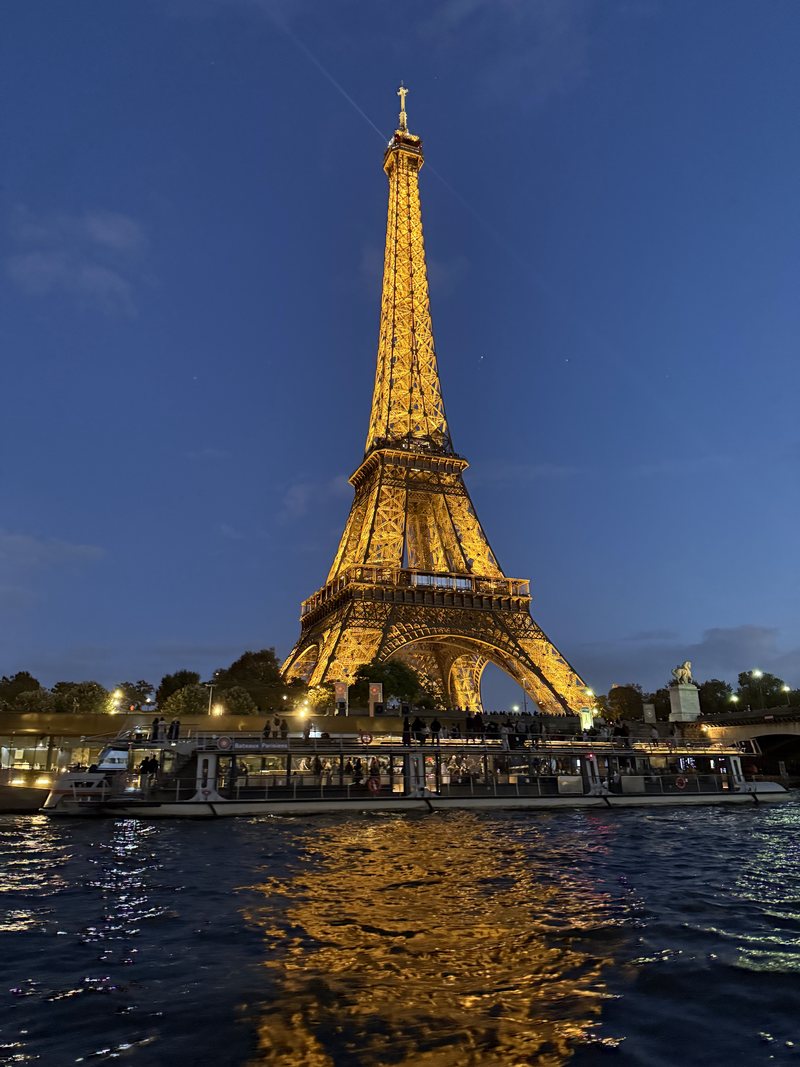 The Eiffel Tower lit gold at night over the Seine