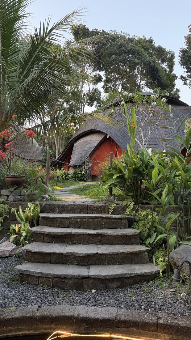 Stone steps leading to thatched huts in a tropical garden